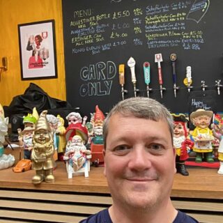 Man in front of garden gnomes in a pub
